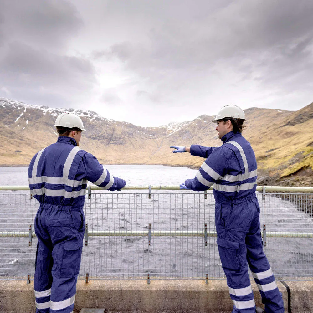 Two utility workers looking out over a body of water